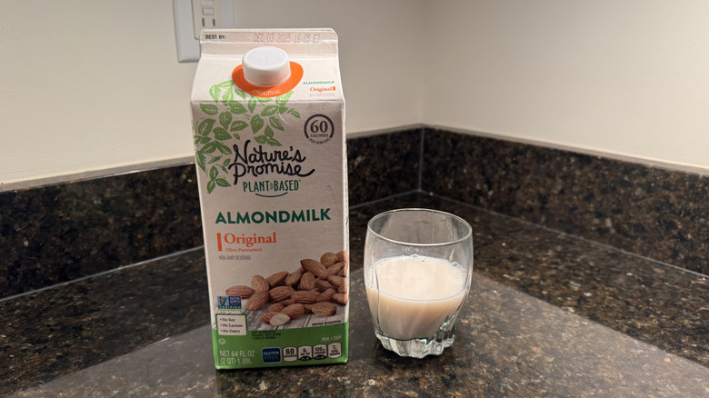 Nature's Promise almond milk with glass on counter