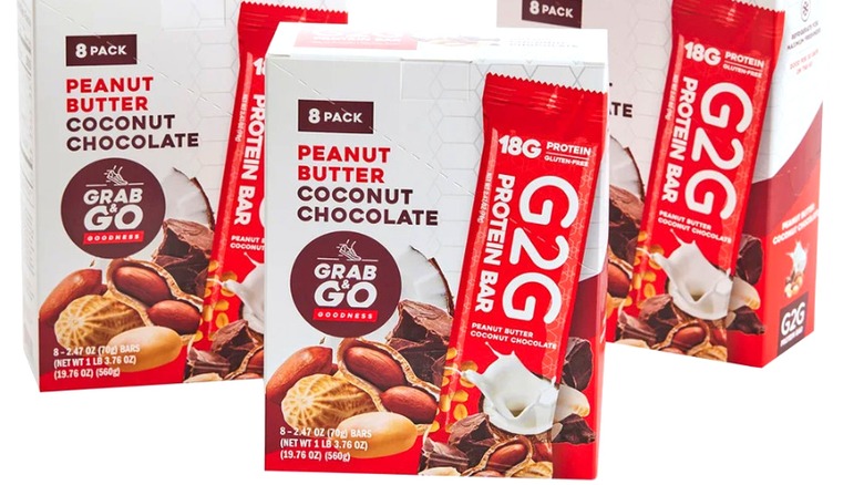 Three boxes of G2G Peanut Butter Coconut Chocolate Protein Bars on a white background