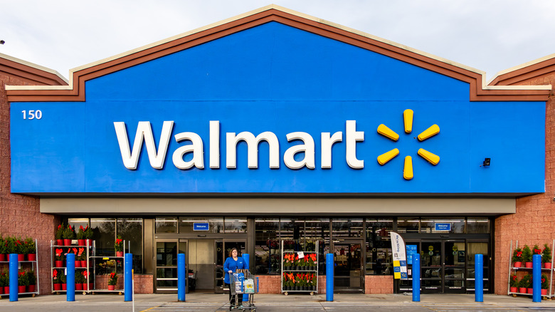 walmart storefront with woman leaving with a shopping cart
