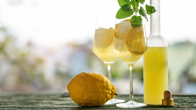 A bottle and glasses of limoncello with a fresh lemon