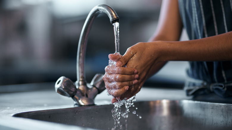 Person washing hands at kitchen faucet