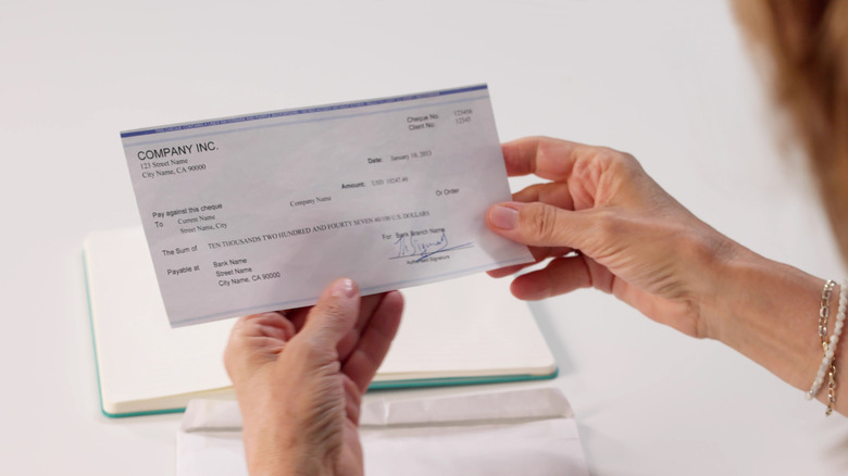 Woman looking down at a paycheck that she's holding