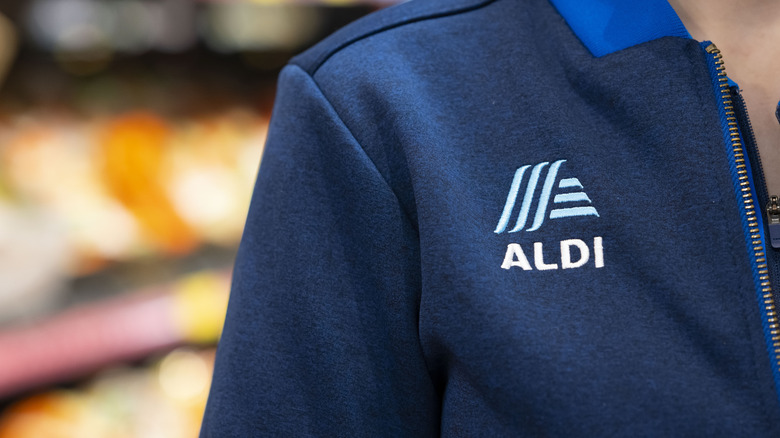 Closeup of an Aldi employee's shoulder, showing the Aldi logo on their uniform shirt