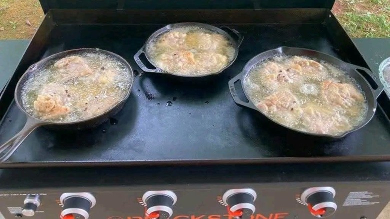 Blackstone griddle with three pans of food on top