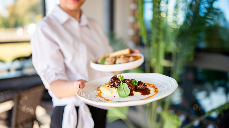 A server at a restaurant carrying two plates