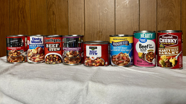 A row of canned beef stews on display, from left Progresso Pitmaster Steakhouse-Style, Dinty Moore, Southgate, Progresso Pitmaster Hearty Smokehouse-Style, Clover Valley, Progresso Beef Pot Road and Country Vegetables, Great Value Beef Pot Roast Soup, and Campbells Chunky Hearty Beef Barley