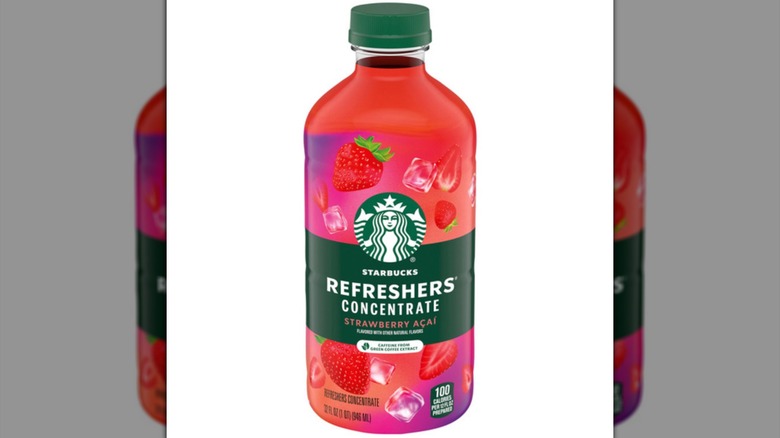 A pink and red bottle of Starbucks Strawberry Acai Refreshers Concentrate with imagery of strawberries and a Starbucks logo.