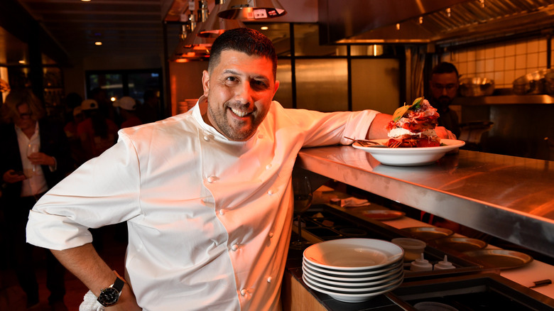 Chef Joe Isidori smiling and leaning on a restaurant kitchen's food window