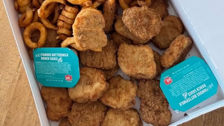 A box filled with Jack in the Box chicken nuggets, sauce, and curly fries