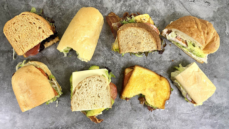 An overhead view of two rows of BLT sandwich halves on a gray surface