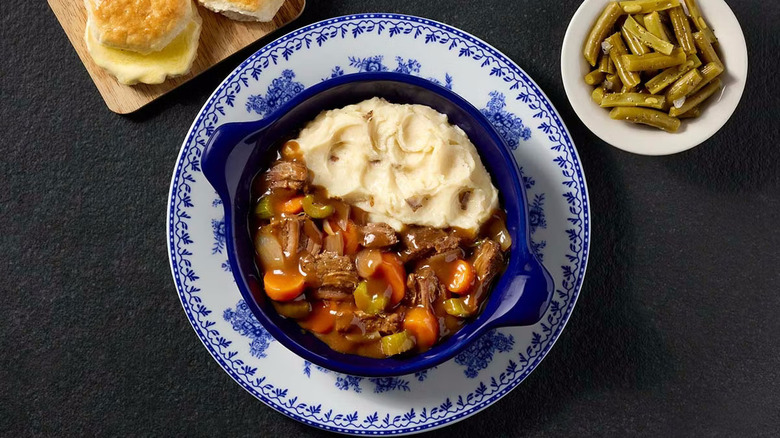 A plate of pot roast with mashed potatoes and sides of biscuits and green beans at Cracker Barrel