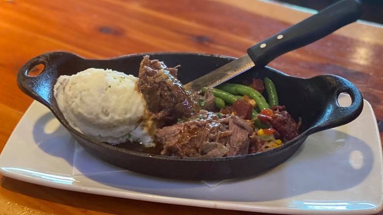 A skillet with pot roast, mashed potatoes, and vegetables at Twin peaks
