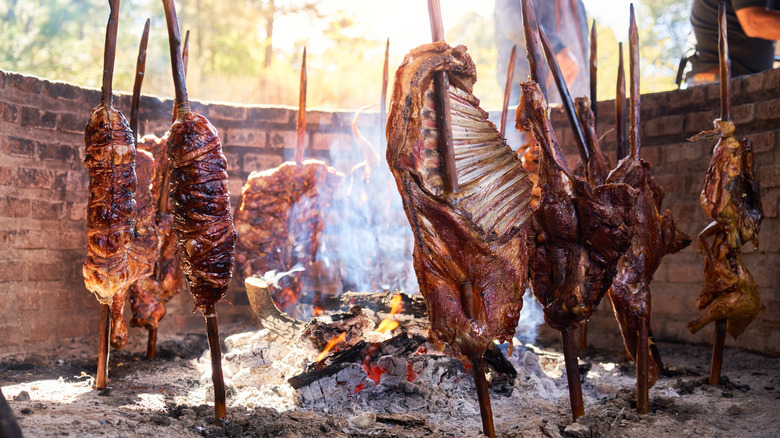 Baby goats or cabrito roasting on pikes around a fire