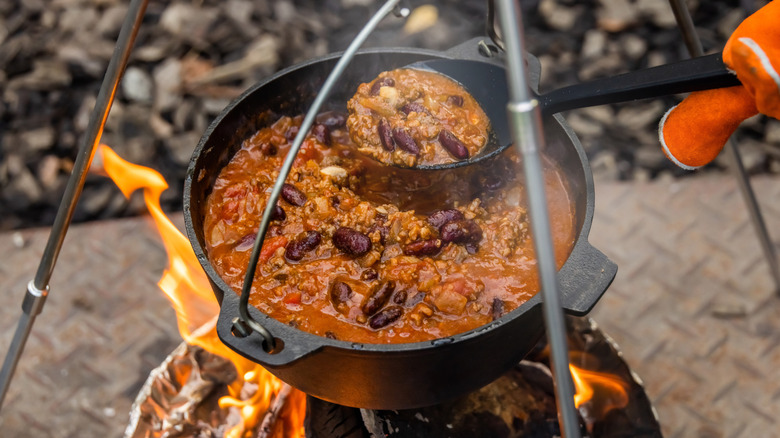Chili in a cast iron pot being cooked over fire