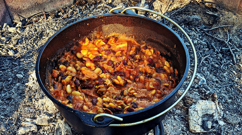 Cowboy beans cooking in a pot over an open fire