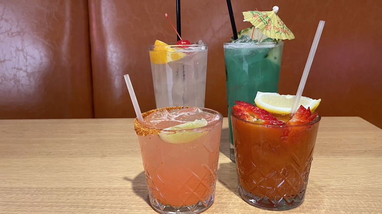 Two tall cocktail glasses and two short cocktail glasses sit on a wooden table.