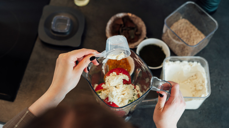 Top-down view of a woman preparing a smoothie in a blender