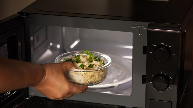 Person putting food in the microwave in a glass bowl