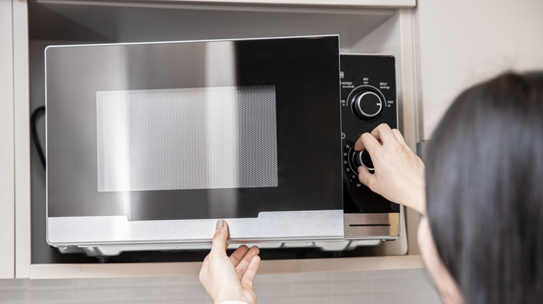 Person adjusting settings on a microwave
