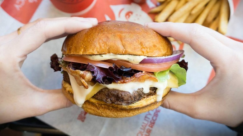 A diner holds the Gouda Baon Cheeseburger from Wendy's