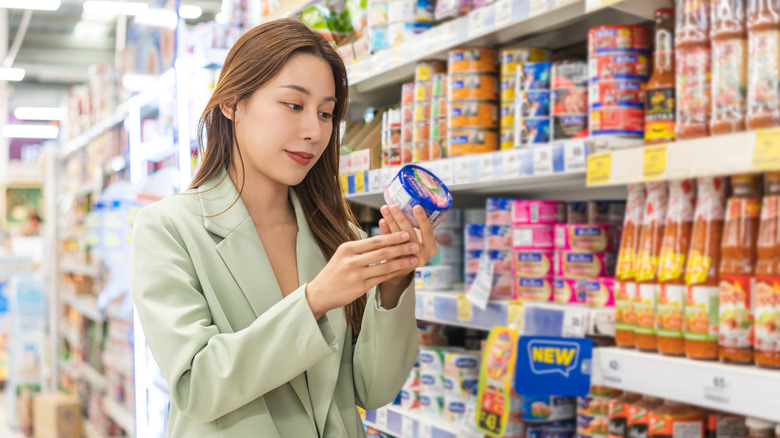 A woman looking at a product label in the store aisle