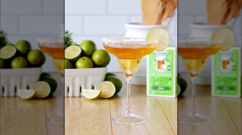 A sweet tea margarita with a lime wedge on a wooden table