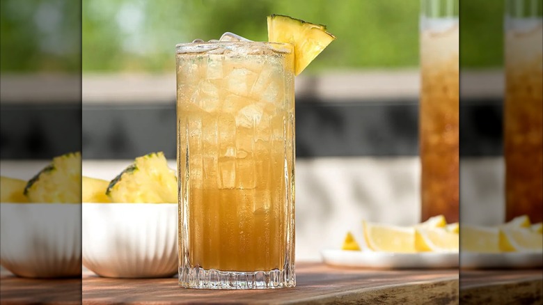 A pineapple bourbon iced tea with a pineapple on the rim