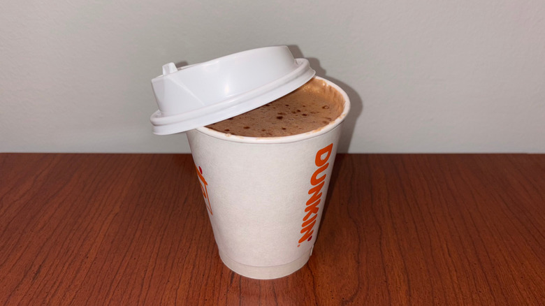 A hot chocolate with darker chocolate bubbles in a Dunkin' to-go cup