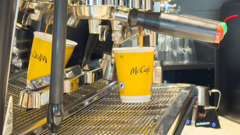 Espresso machine pouring coffee into a bright yellow McCafe cup,