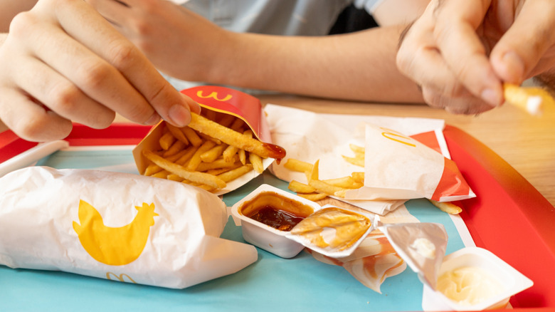 two mcdonald's dips on a tray with people dipping fries in them