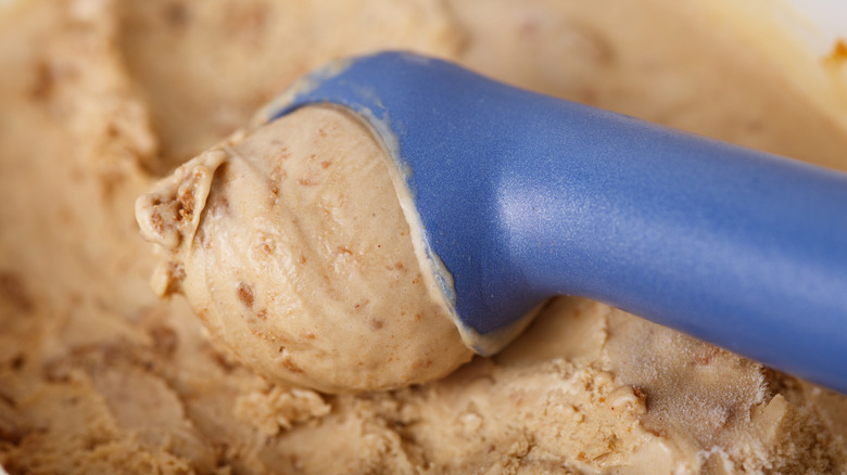 Caramel-colored ice cream is scooped from a container