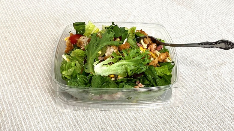 a fast food salad with a fork inside on a table