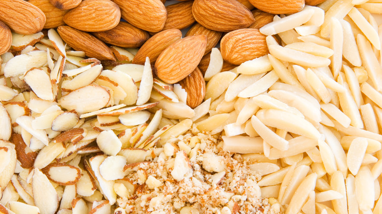 An overhead view of whole almonds along with almonds that have been crushed, sliced, and finely chopped.