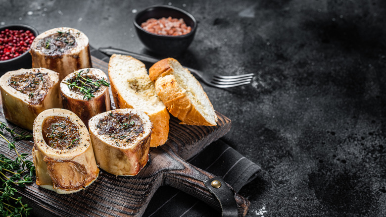 Roast marrow bones on a wooden board with slices of bread