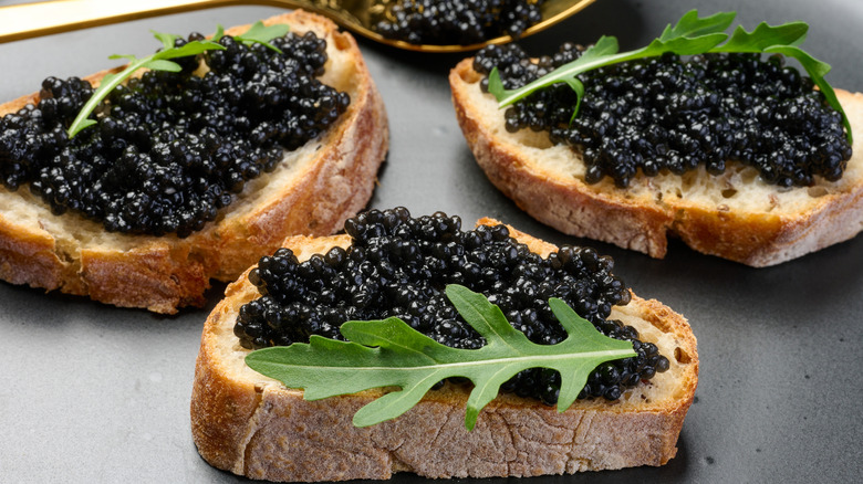 Black caviar on toast with arugula garnishes