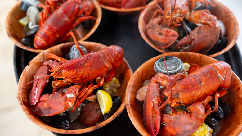 Five wooden bowls with lobsters, corn, and potatoes