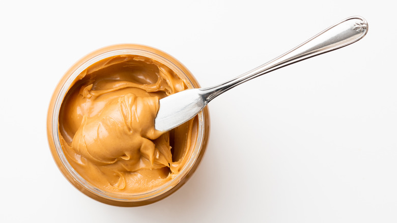 a jar of smooth peanut butter with a knife inside