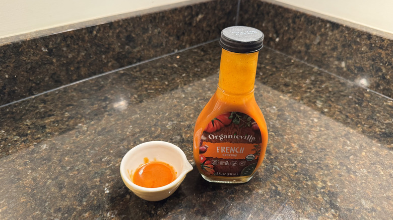 Organicville salad dressing on a counter next to small white dish containing dressing