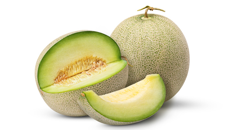 A slice of honeydew is cut from the whole melon