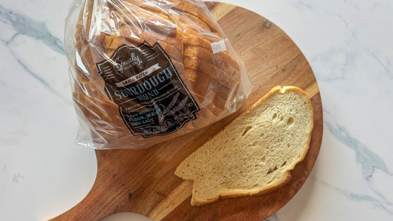 Specially Selected small-batch sourdough bread in package with a slice sitting on wooden cutting board