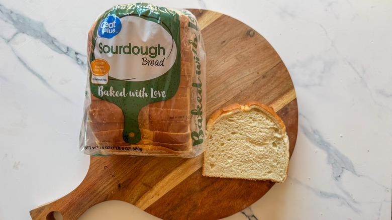 Great Value sourdough bread in package with a slice on a wooden surface