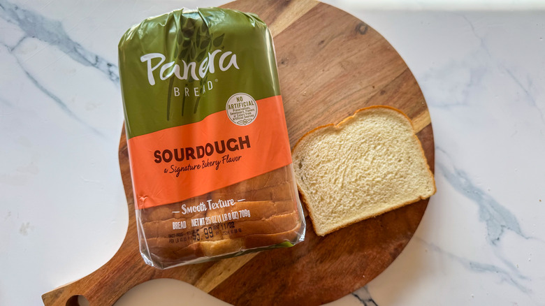 Panera Bread sourdough loaf in package with one slice on wooden surface