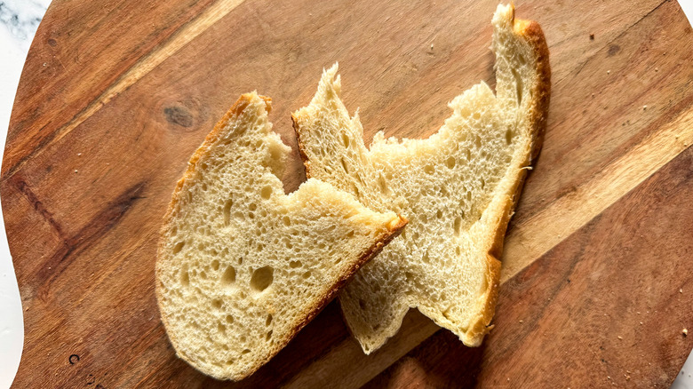 Two partial slices of bread on a wooden surface