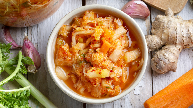 A bowl of kimchi surrounded by ingredients like ginger.