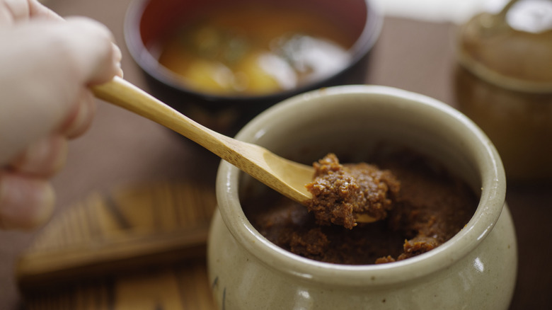 Miso paste being spooned out of a ceramic jar.