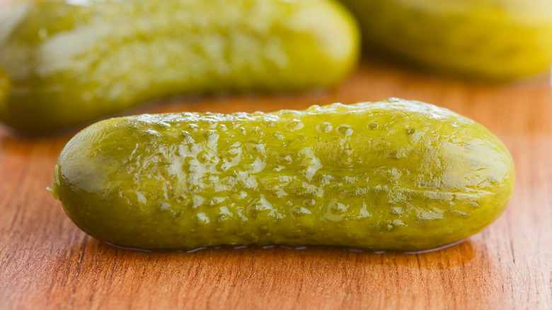 A pickled cucumber on a wooden board.