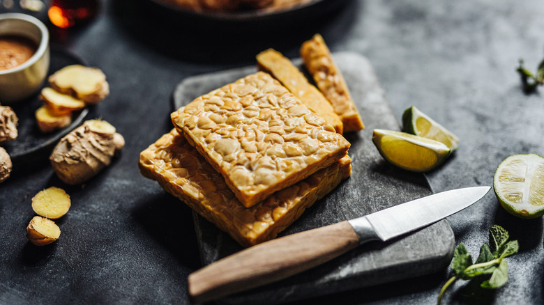 Sliced tempeh on a cutting board with a knife on the side
