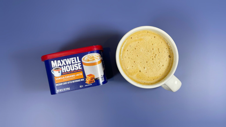 Maxwell House's container of vanilla caramel latte next to a mug