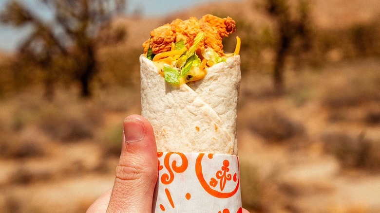 Popeyes chicken wrap on paper in hand