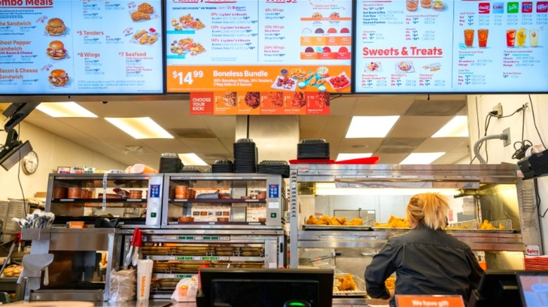 Popeyes employee behind counter, under menu